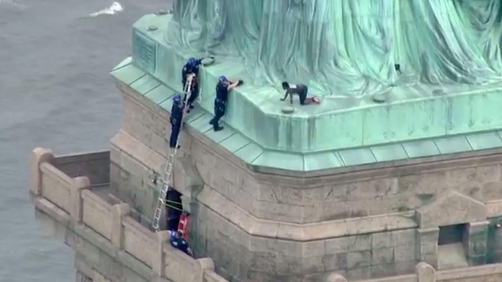 Police talking to a woman who climbed to the base of the Statue of Liberty in New York on July 4, 2018