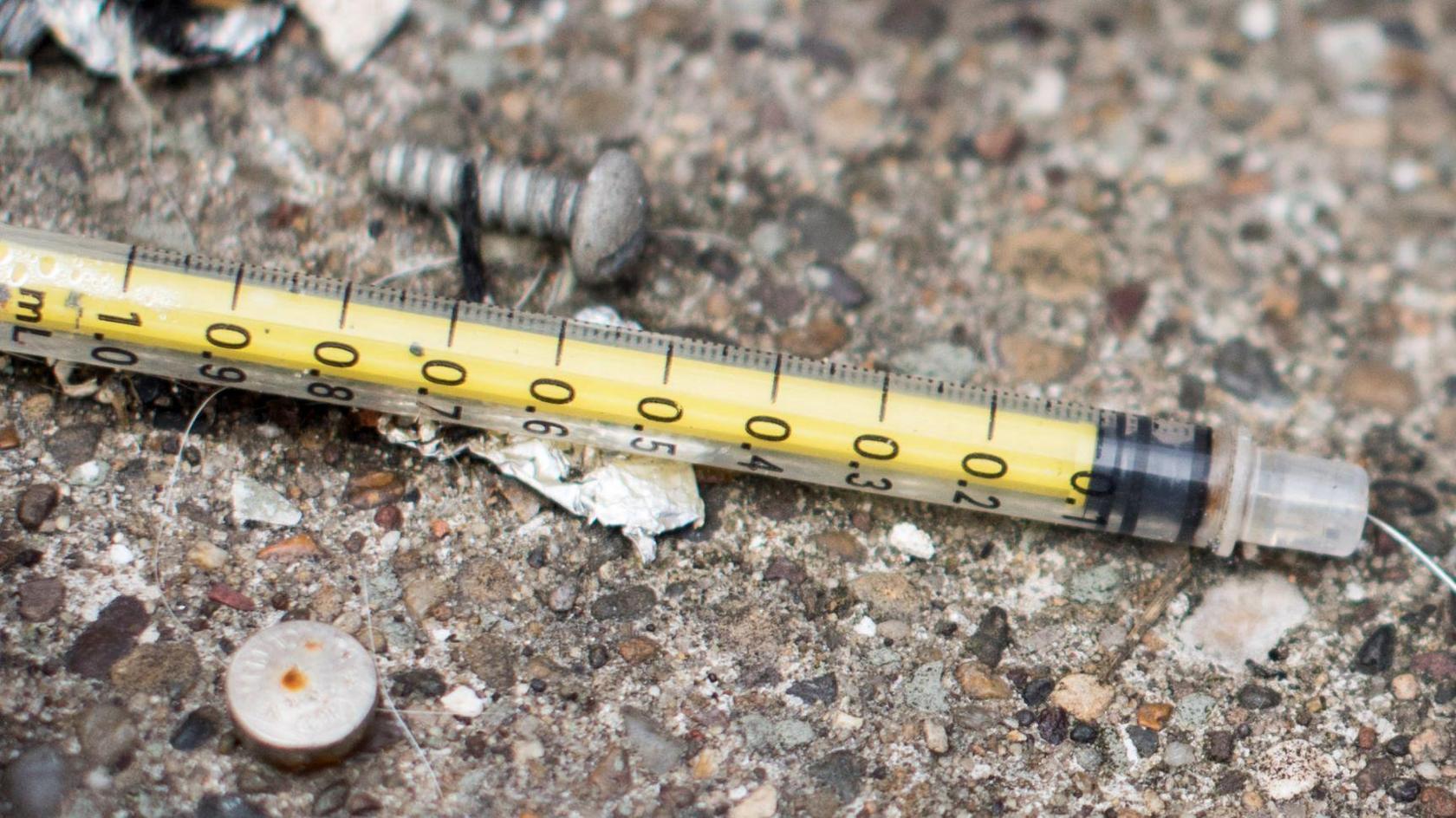 General view of syringe used for injecting heroin, thrown on floor amongst litter