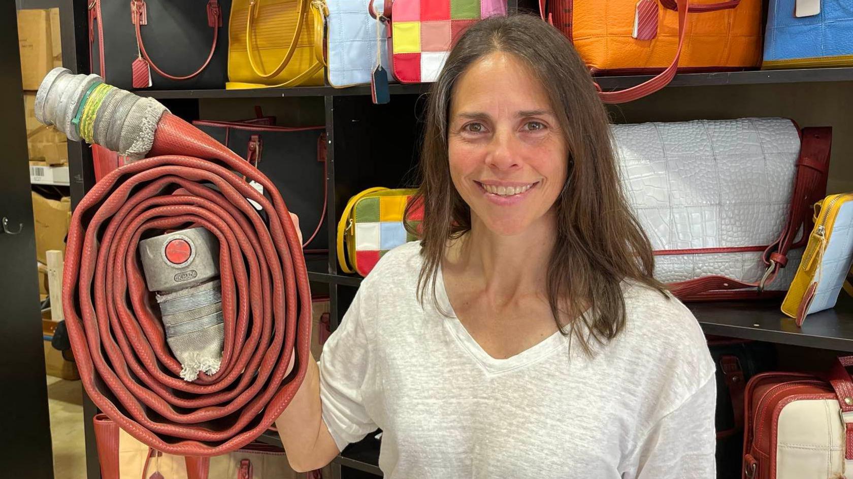 Kresse Wesling holding firehose in front of Elvis & Kresse firehose bags