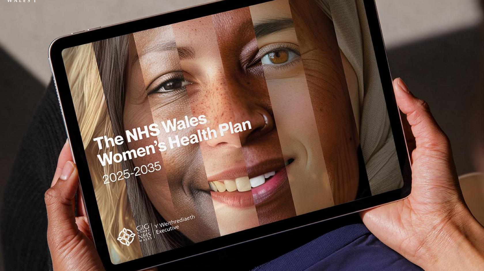 A laptop is held in a woman's hands. The image on the device is a woman's face, made up from a composite of eight different women's faces, each with a different skin tone. 
The words on the image read "The NHS Wales Women's Health Plan 2025-2-35" with the NHS Executive logo beneath. 