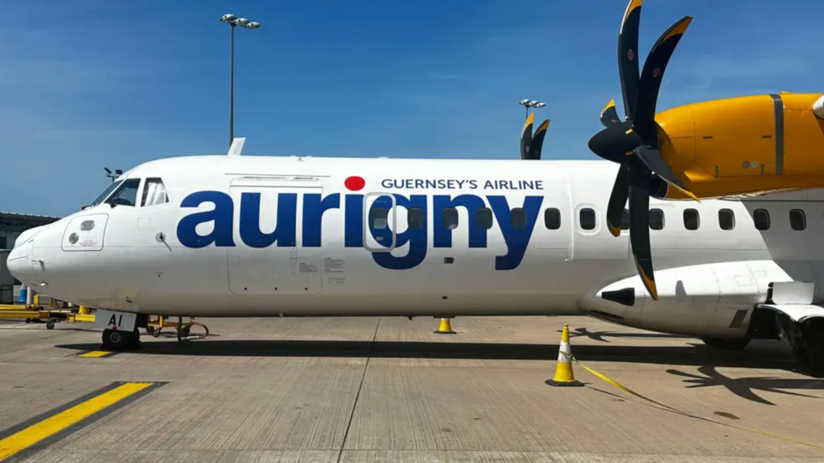 The side of a plane. It has Aurigny livery in blue colour text.