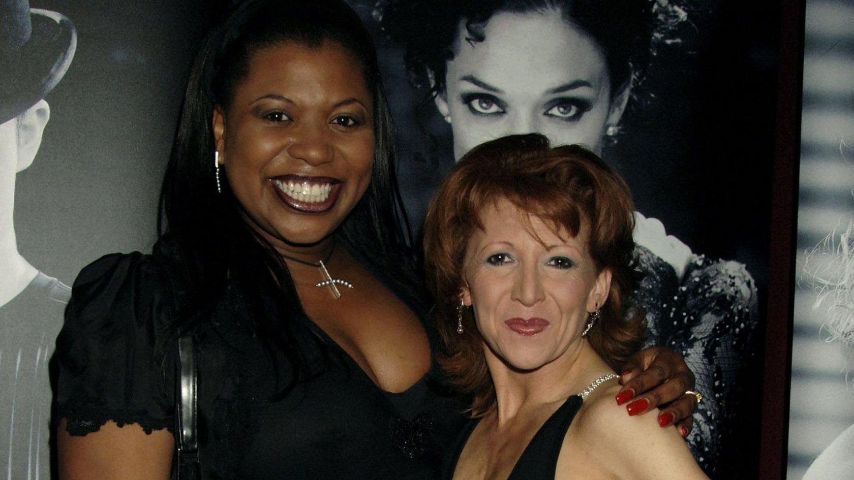 Brenda Edwards smiling in a photo from 2006 with Bonnie Langford. Both dressed in black dresses and stood in front of a Chicago publicity back drop