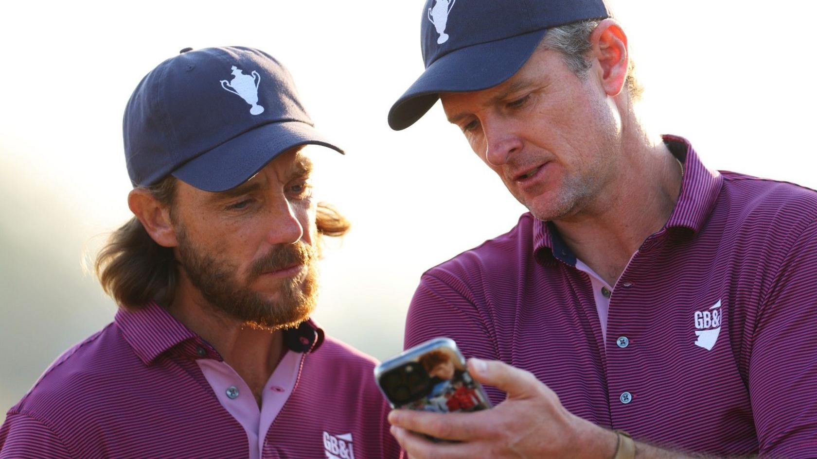 Tommy Fleetwood and Justin Rose look at a mobile phone during day one of the Team Cup