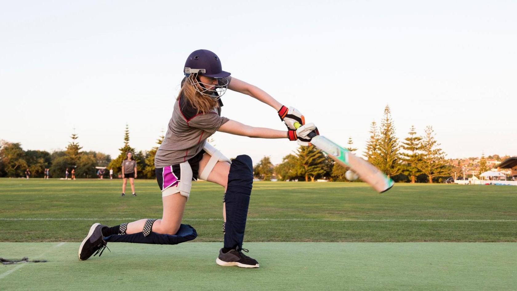 A girl playing a cricket drive