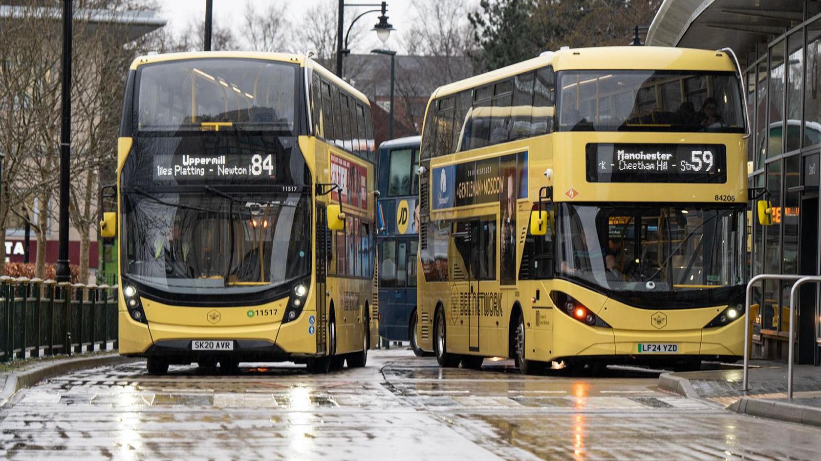 Two Bee Network buses on a road on a wet day