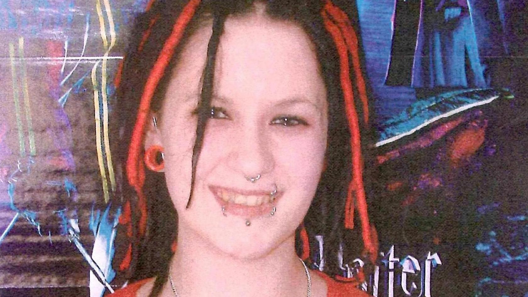 A young woman with red and black hair and nose and lip piercings