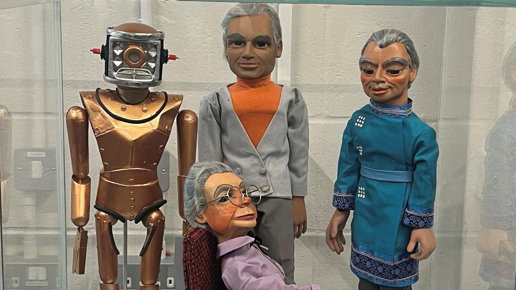 Puppets from Thunderbirds behind glass alongside other memorabilia from the show