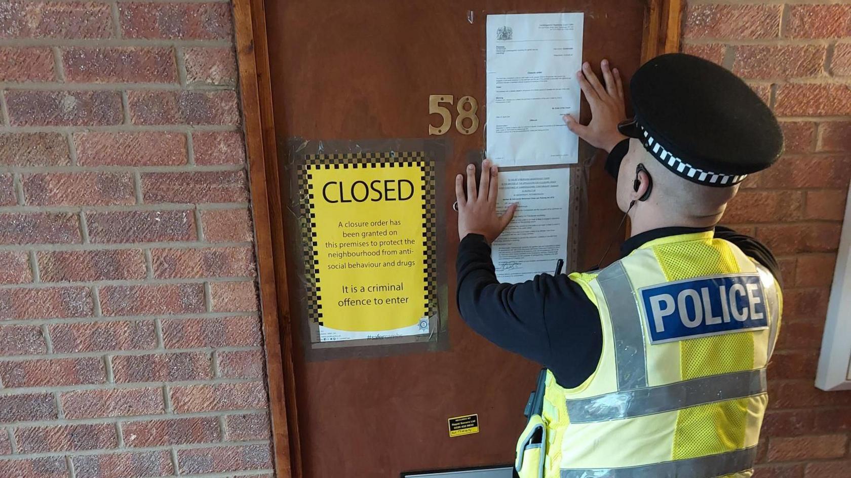 A police officer posting an extension to the Closure Order on 58 Wainwright