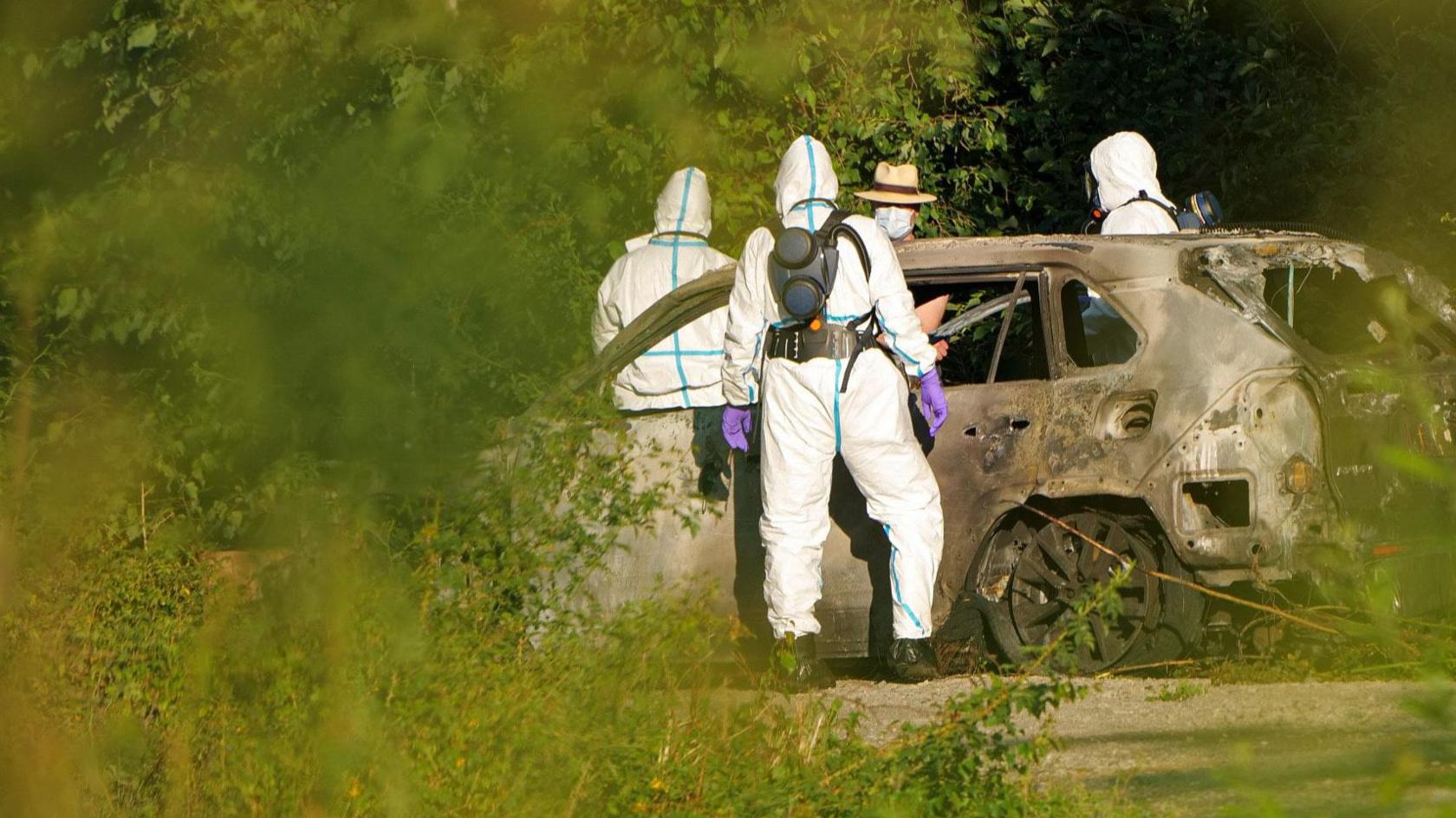 Police in Malmo pictured investigating a burnt out car.