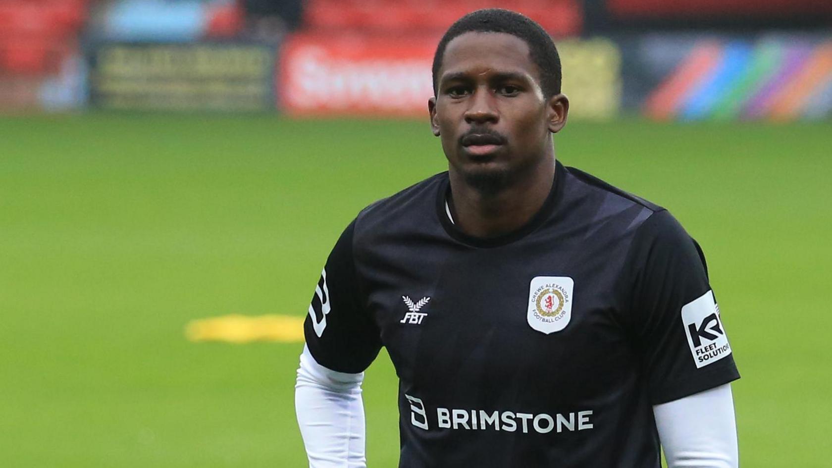 Crewe striker Shilow Tracey in his training kit, going through some warm-up stretches before a game