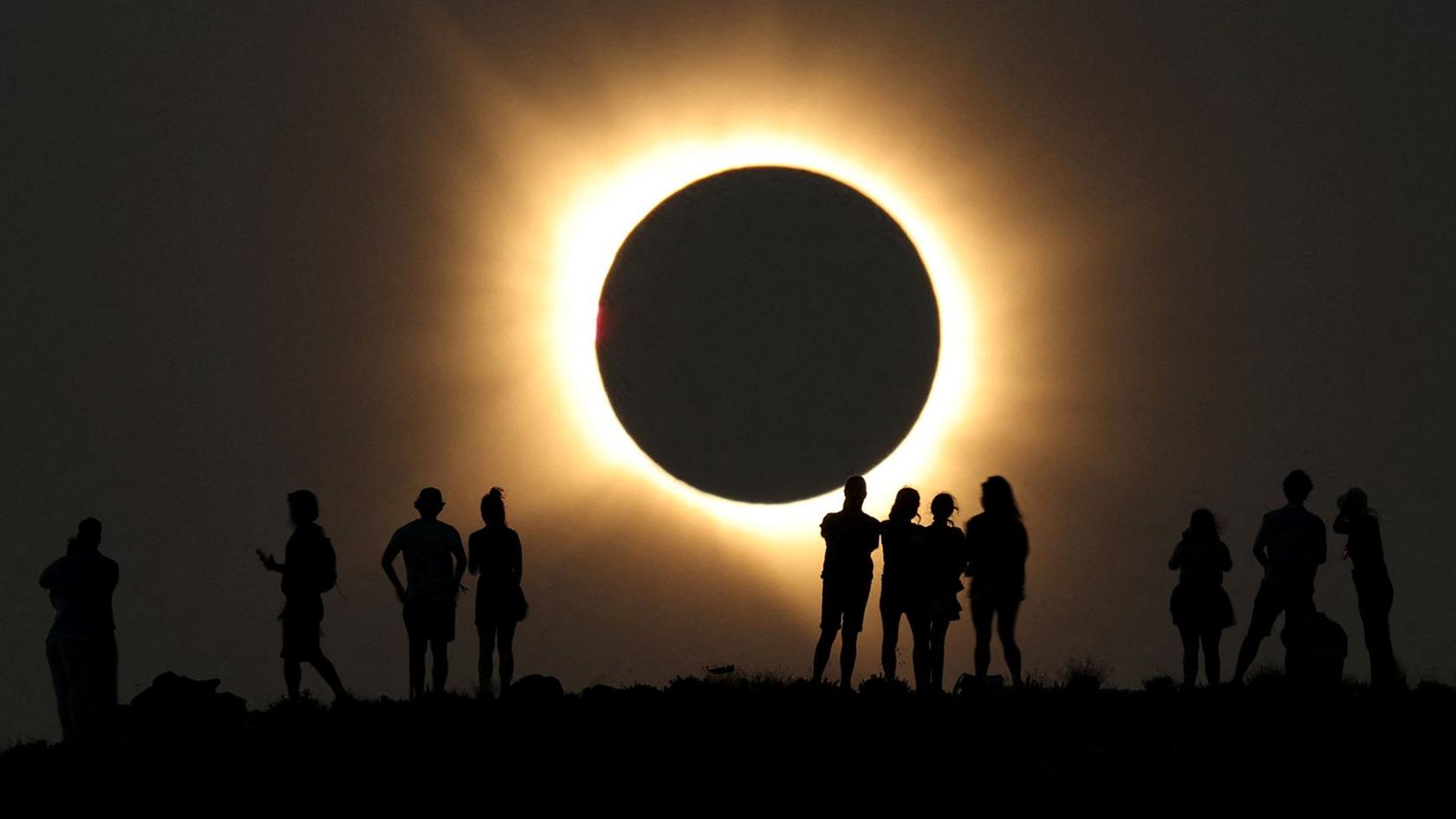 Full eclipse with silhouetted people watching in Arcos de las Salinas, Spain