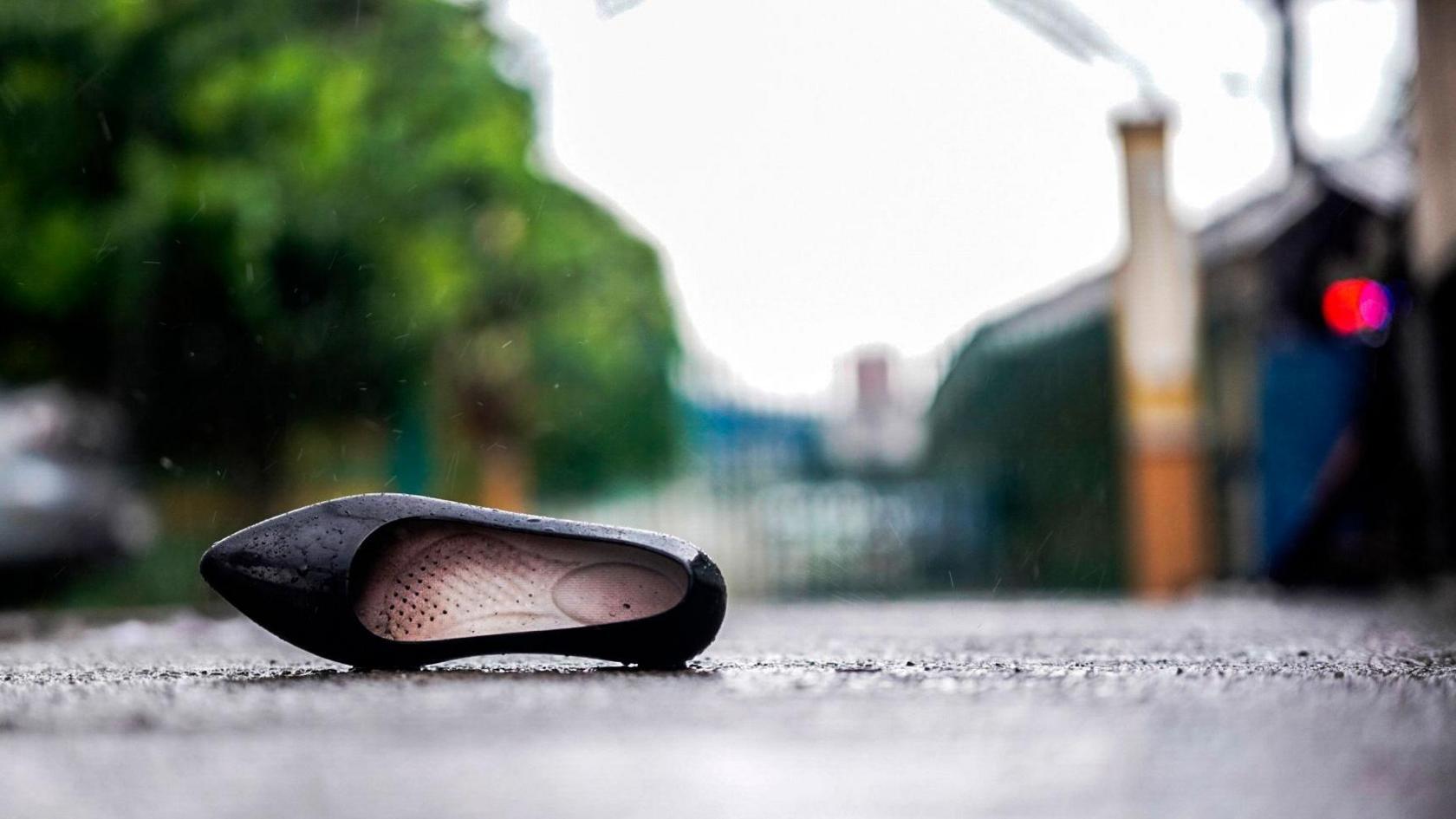 The right side par of a black school shoe lays on the payment after the Tacloban high school mass shooting in the Philippines