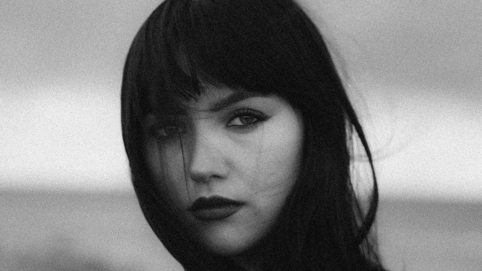 Black and white close-up of Megan Wyn with long dark hair and a fringe 