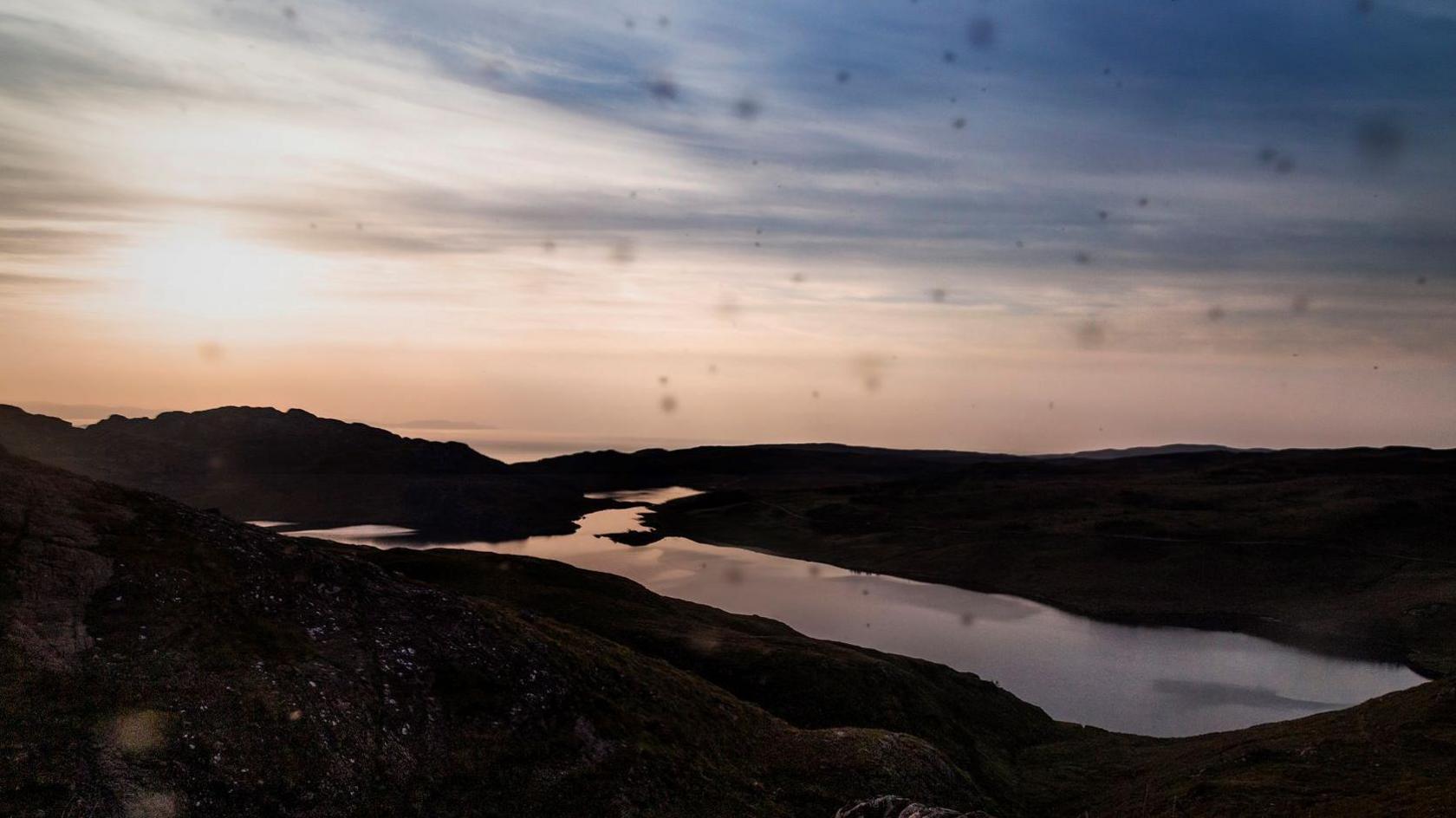 Midgies cover the lense of a camera like little blurry dots in a picture taken near Torridon