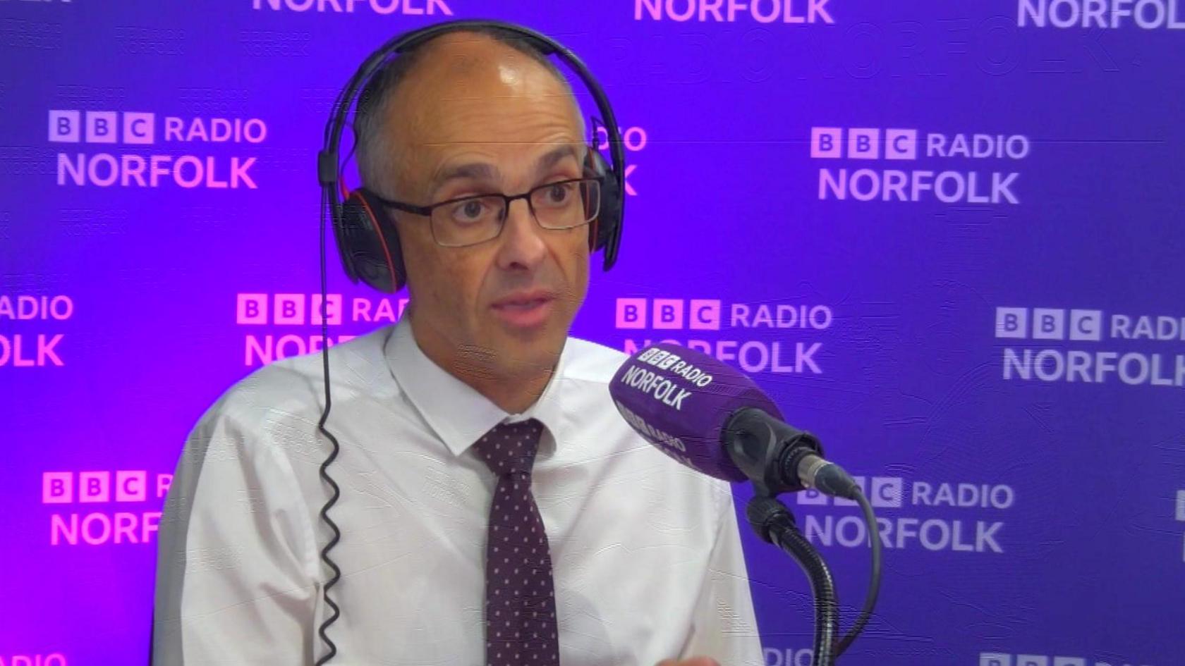 Chief Constable Paul Sanford sitting in front of a BBC Radio Norfolk microphone