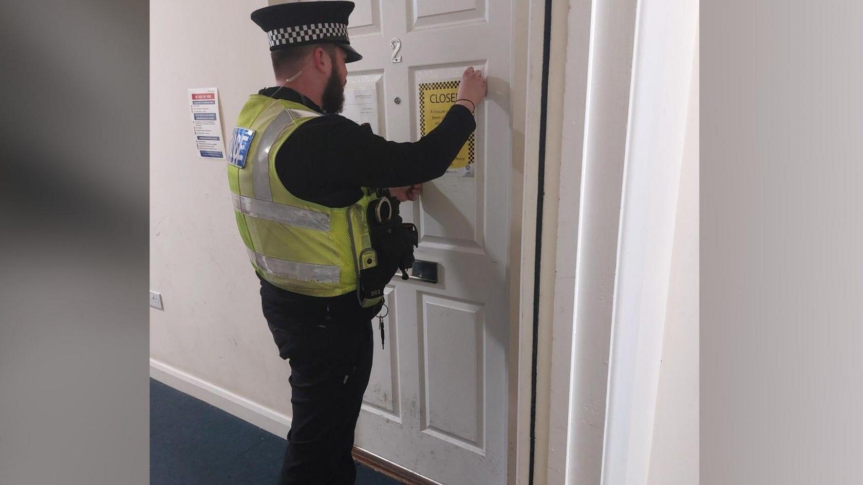 Police officer placing a closure notice on the door 