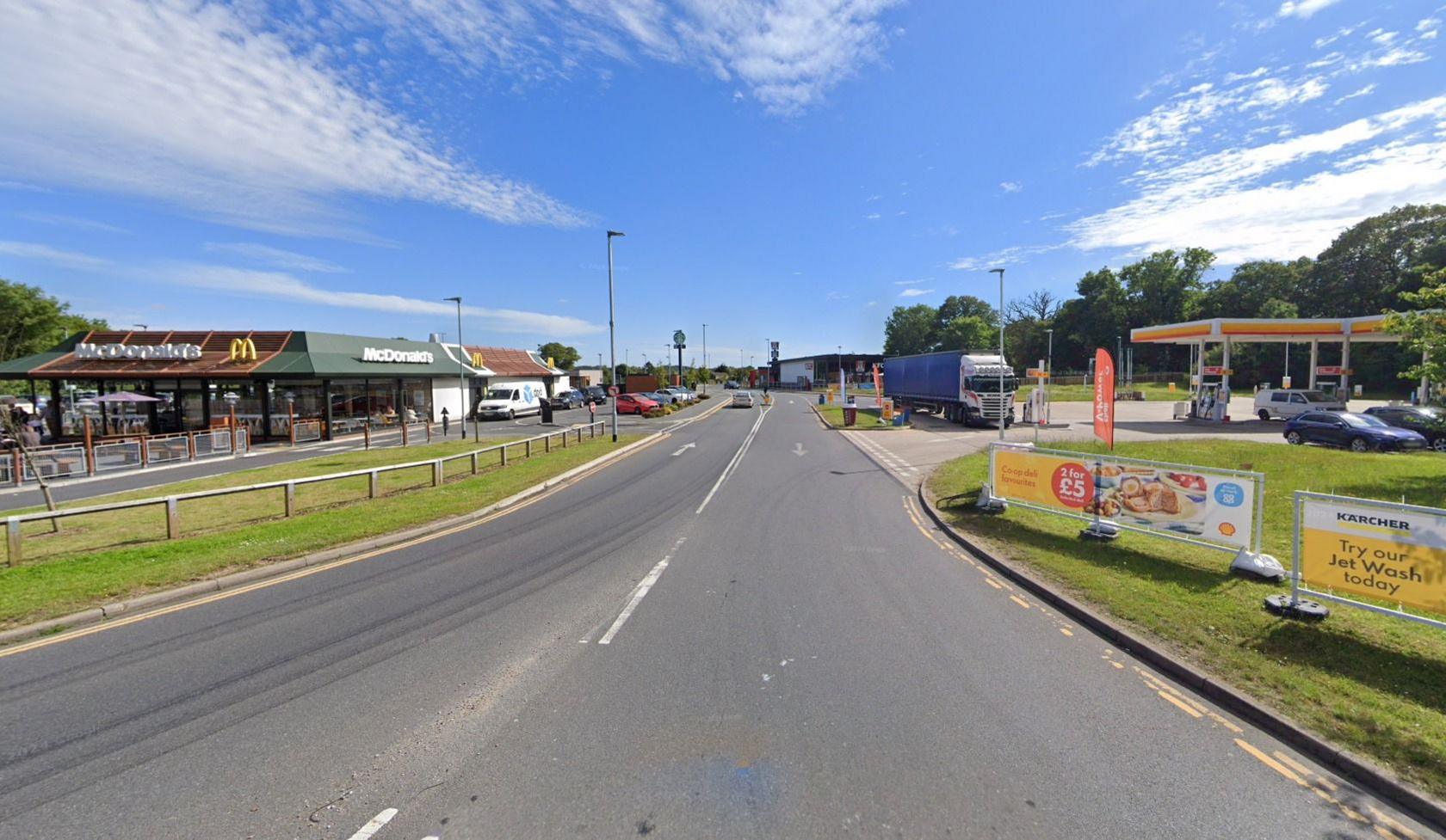 A road with a McDonald's to the left and a petrol station to the right. There is a lorry on the petrol forecourt and it is a clear, sunny day.