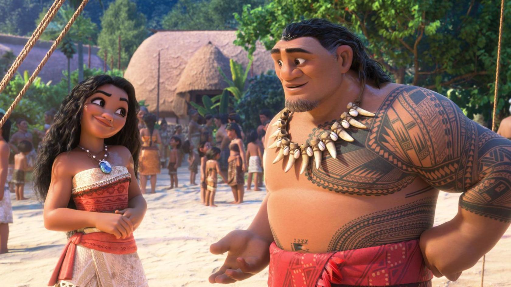 A still from Moana 2, with the main characters on a Polynesian island, with lots of different characters on the beach in the background. There is a straw hut and lots of trees.