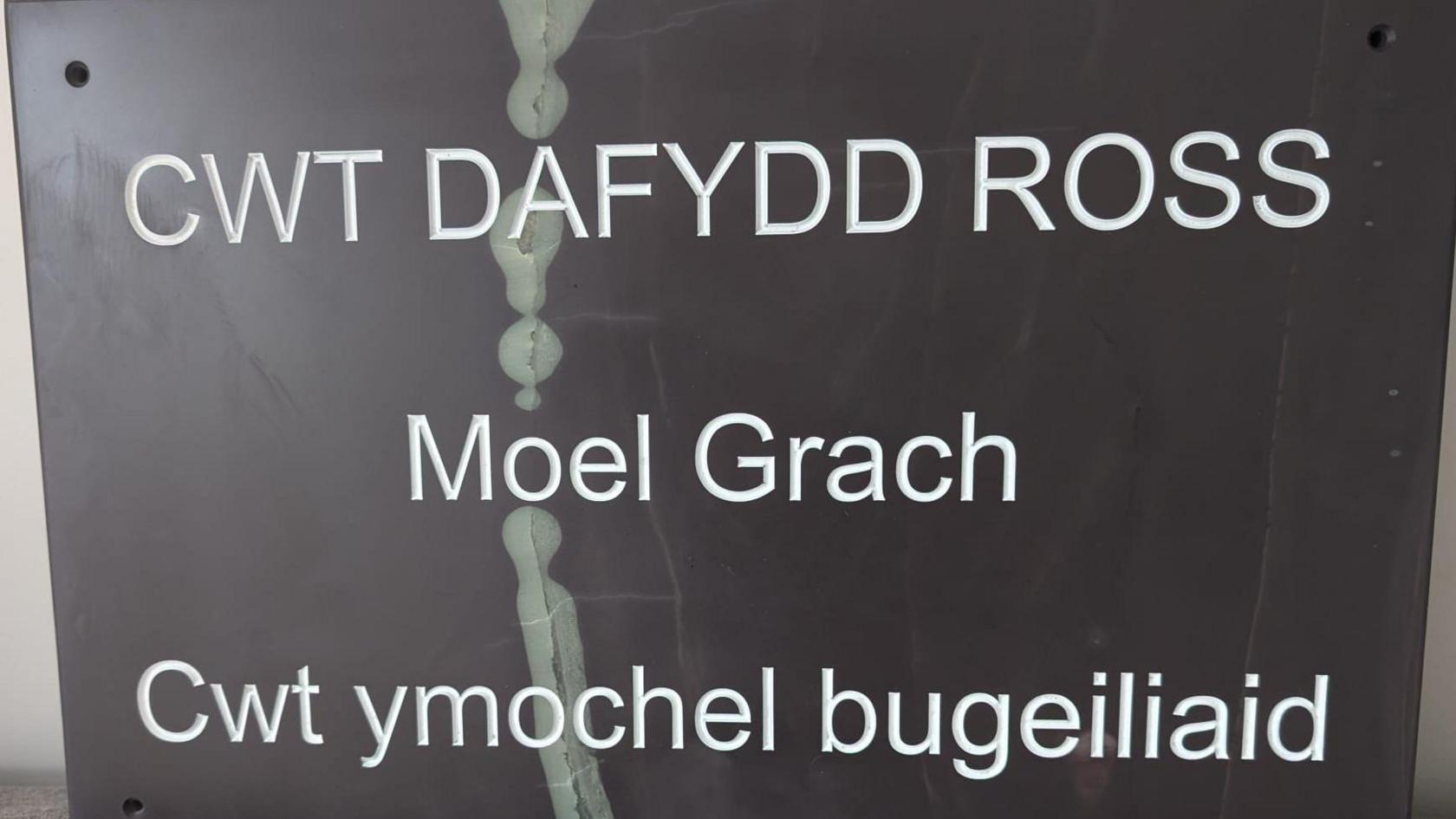 Arwydd Cwt Dafydd Ross - llechen hirsgwar gyda llythrennu gwyn