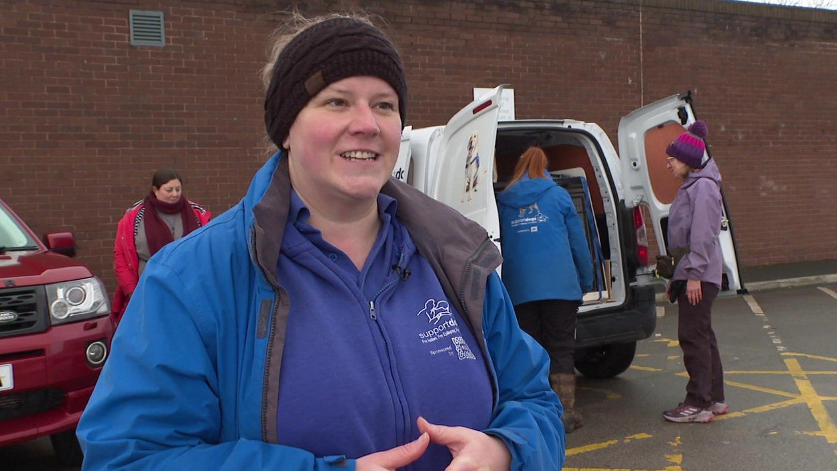 Support Dogs UK puppy coordinator Karlie Wordsworth speaking in front of a charity van.