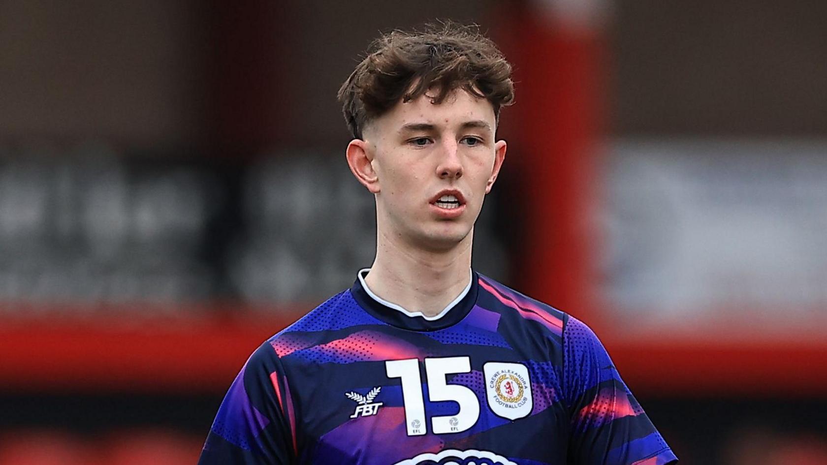 Joe White warming up for Crewe Alexandra during his loan spell with the club. He is wearing a purple and pink away shirt.
