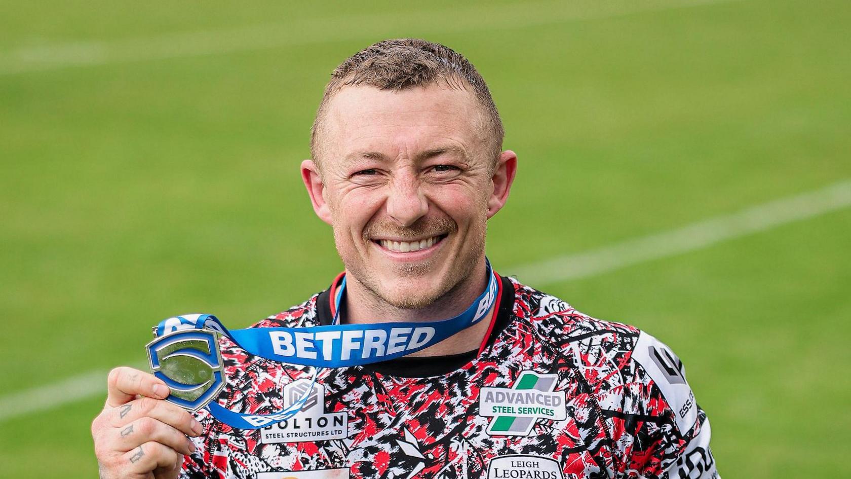 Josh Charnley holding up a silver Player of the Match award in his right hand while it's hanging around his neck following Leigh's win at Bradford