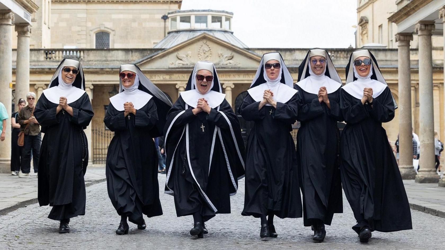 Members of the cast of Sister Act walk in a line through the centre of Bath near the Theatre Royal