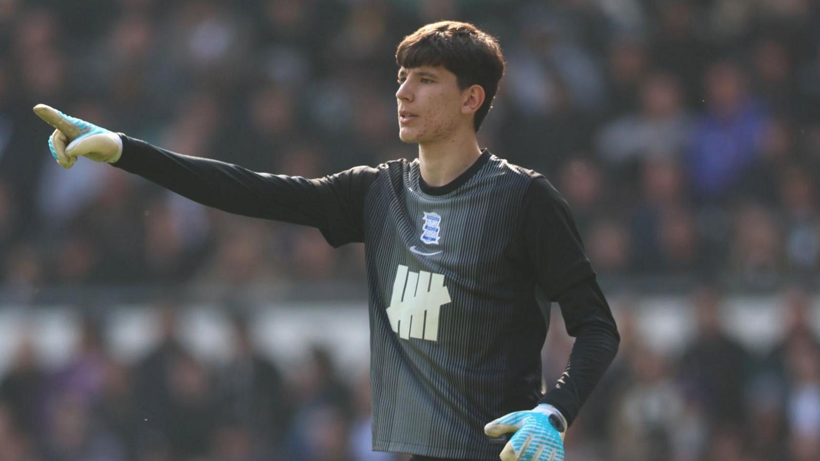 A photo of James Beadle directing his team-mates while playing for Birmingham City in their black goalkeeping kit and blue gloves in March