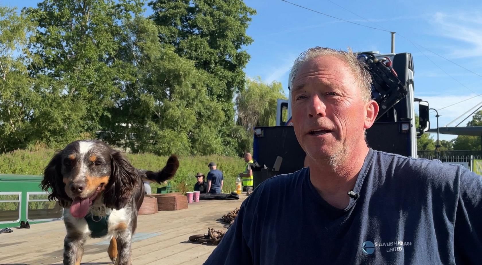 Kevin Ellison leaning on a flatbed truck with his dog standing on the truck next to him