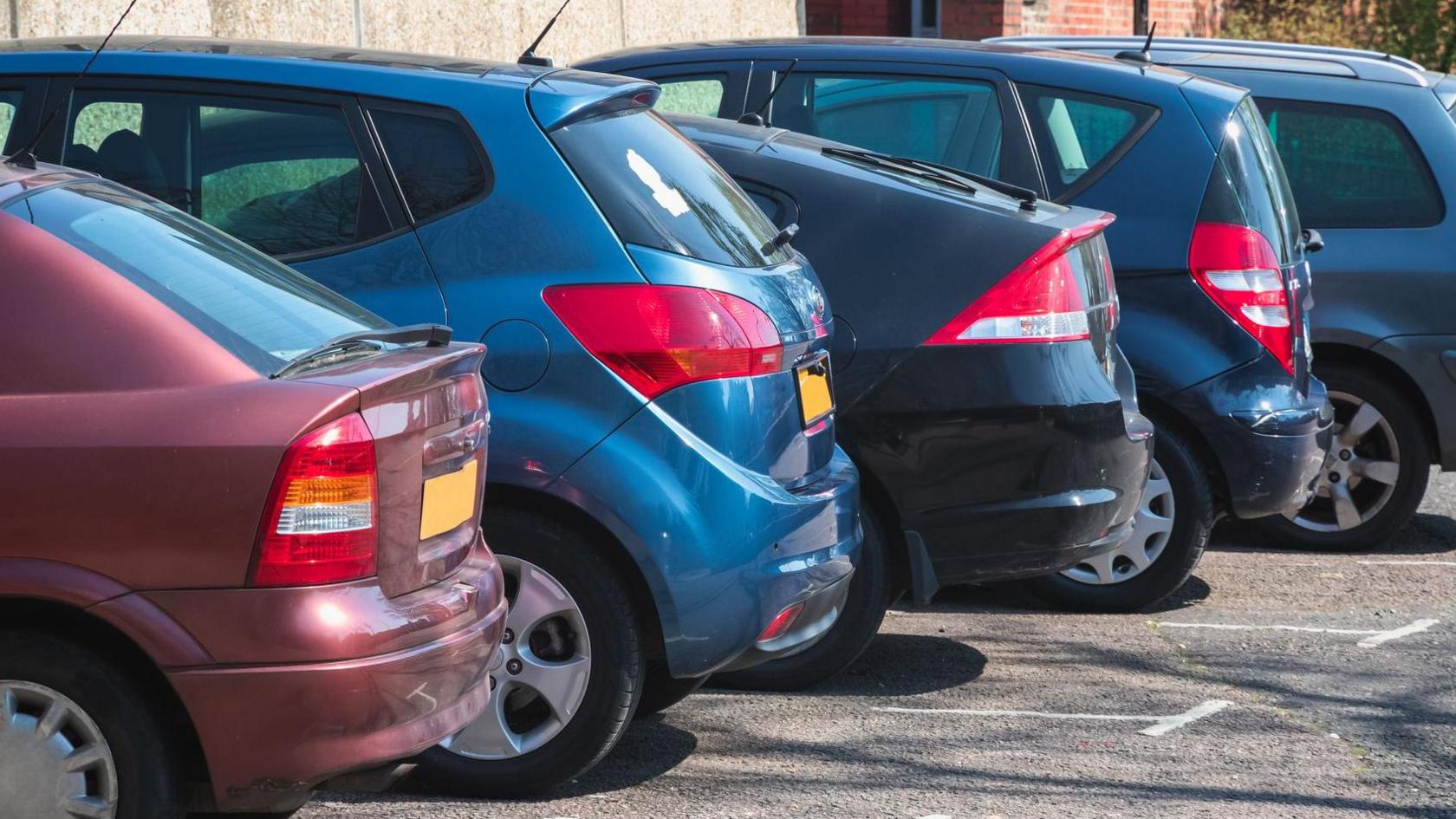 The boot-side of five parked cars 