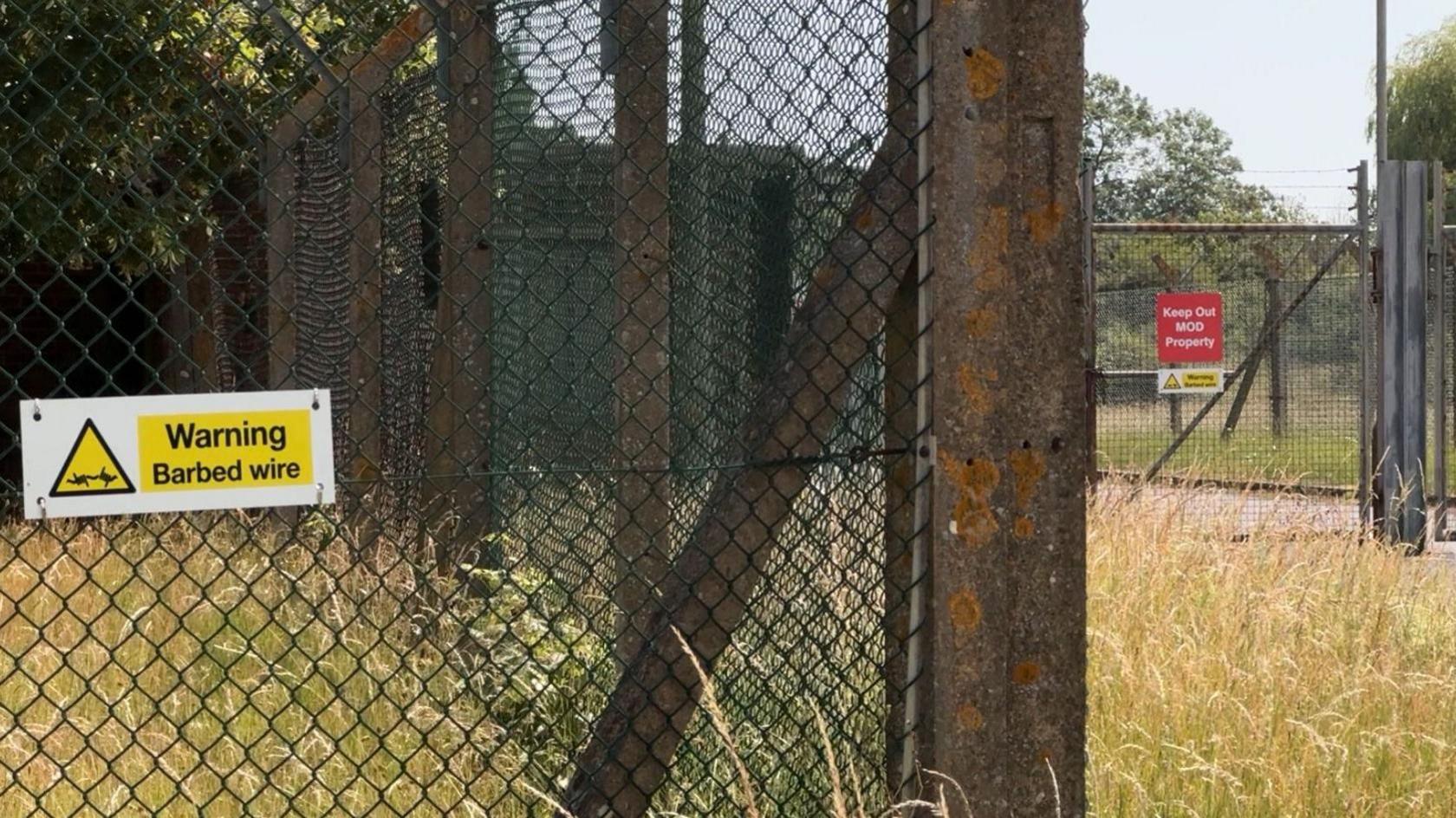 Barbed wire fencing around a former military site near Piddington in Oxfordshire. 