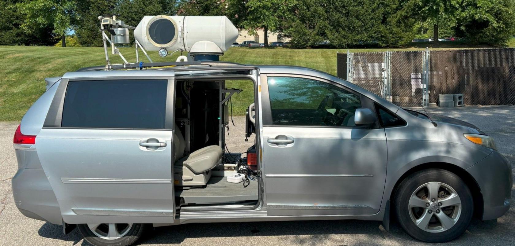 A car with a periscope on the roof to carry light to a UV camera