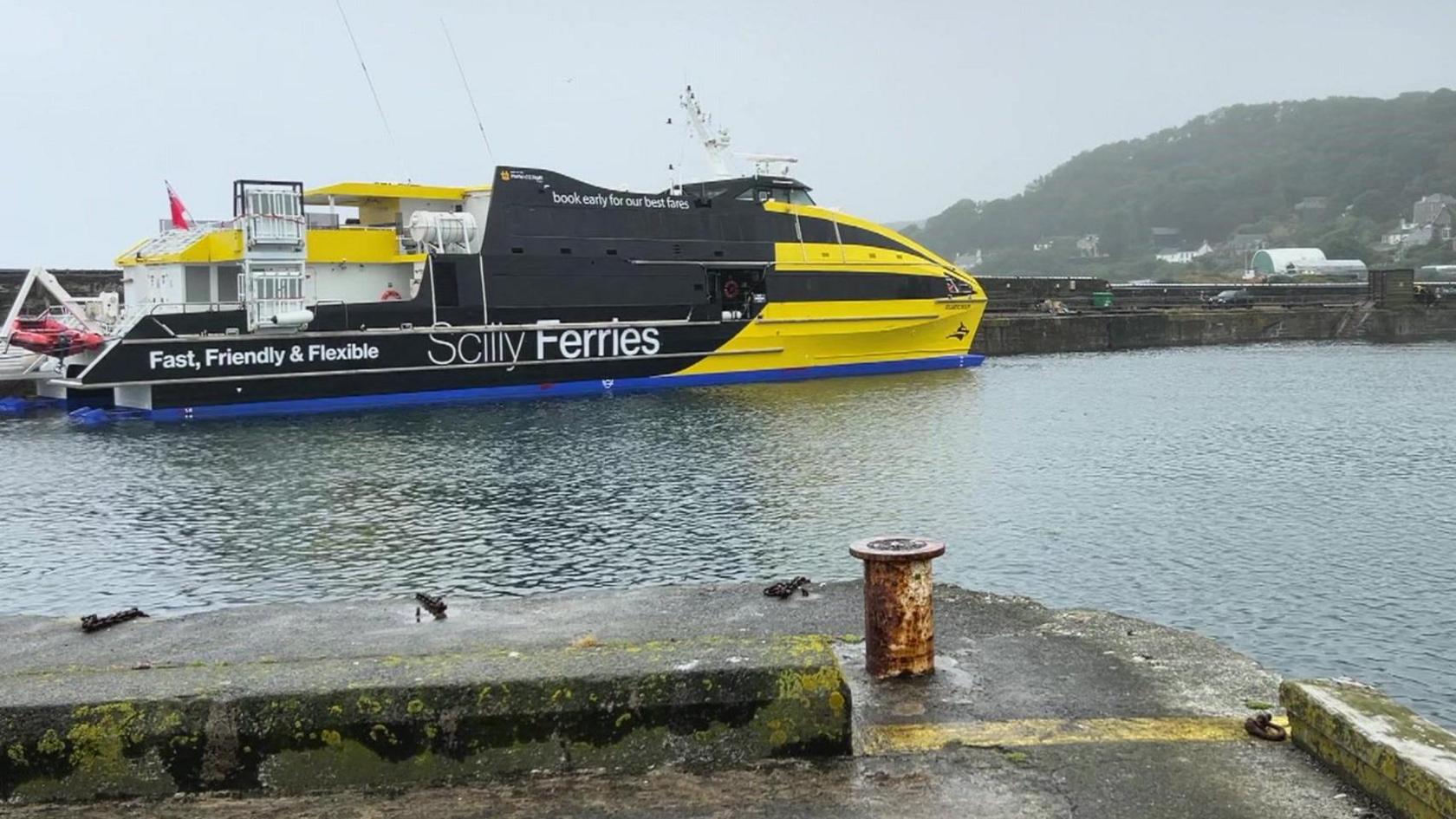 The bright yellow and black Scilly Ferries vessel moored in the harbour in Penzance on a grey day