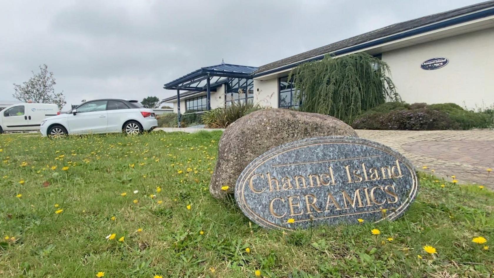 A stone sign saying Channel Islands Ceramics rests on some grass with a one-story building behind it.