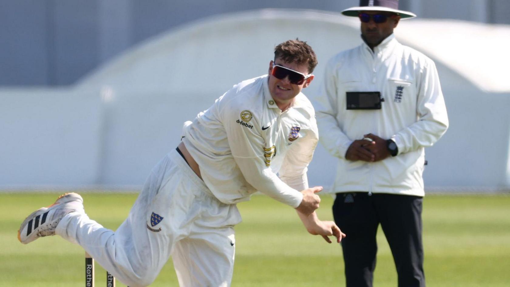 Jack Carson bowling for Sussex with an umpire standing in the background