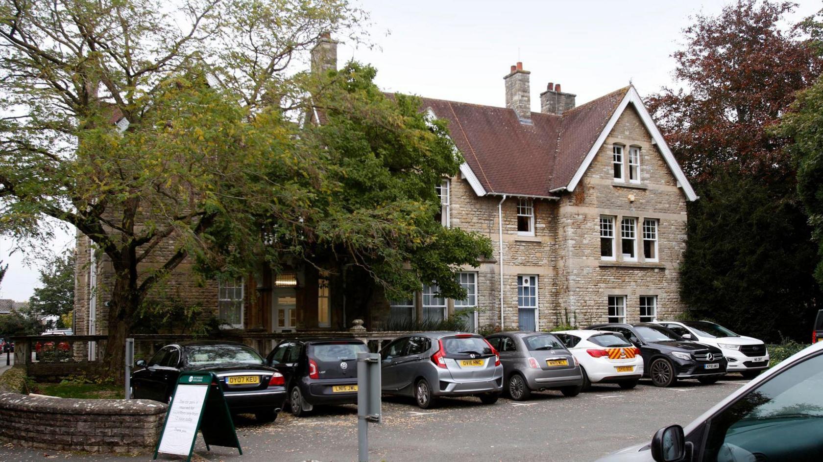 The offices of West Oxfordshire District Council in Woodgreen, Witney. A view from the front of the building with the car park full of cars on an overcast day.