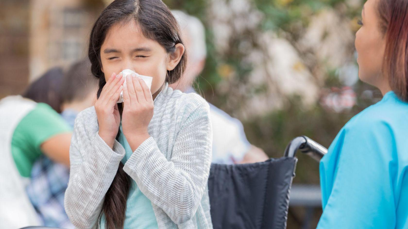 girl in a wheelchair blowing her nose