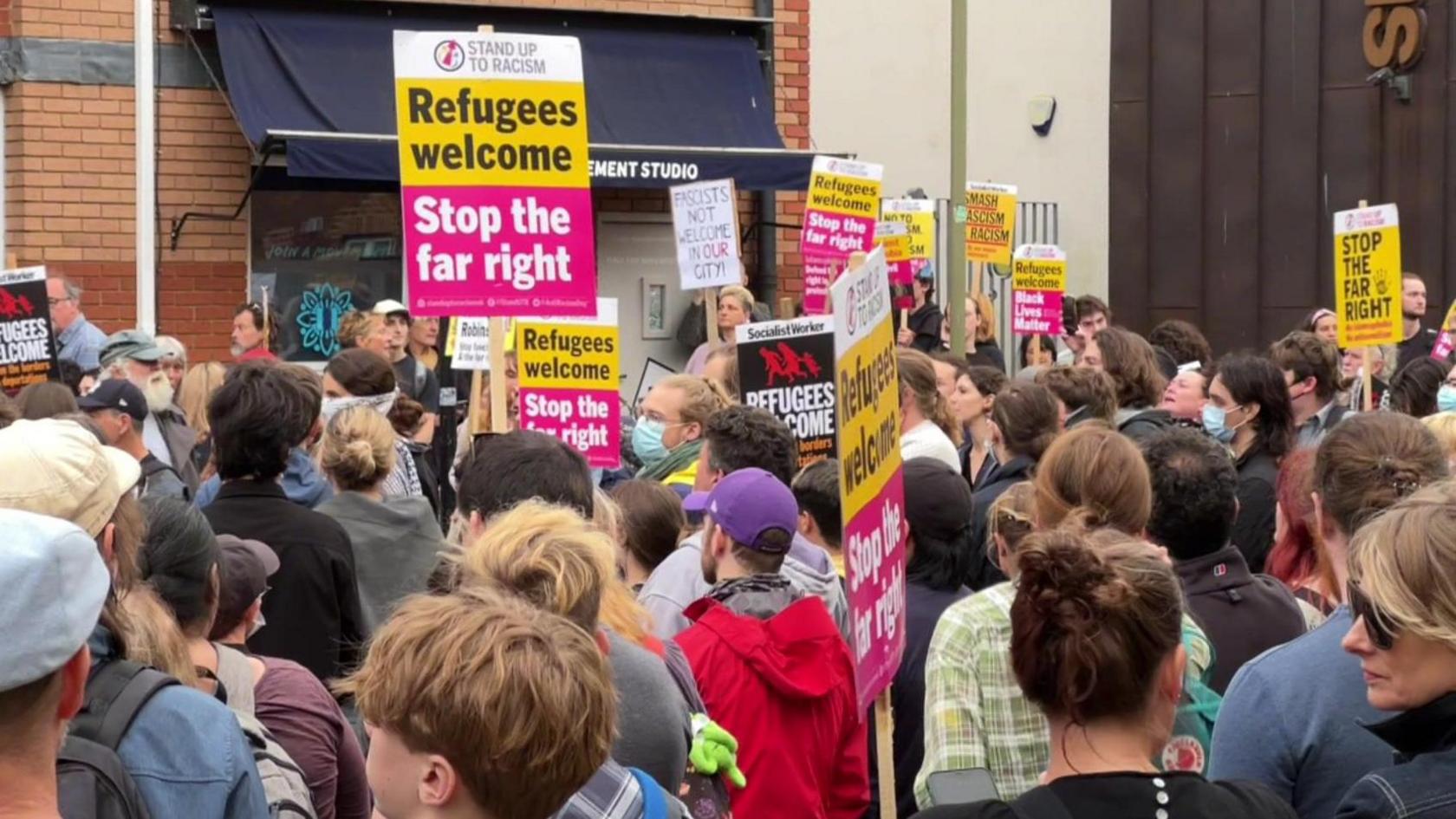 A crowd gathered outside Asylum Welcome in Oxford, holding banners that say "Refugees welcome. Stop the far right".