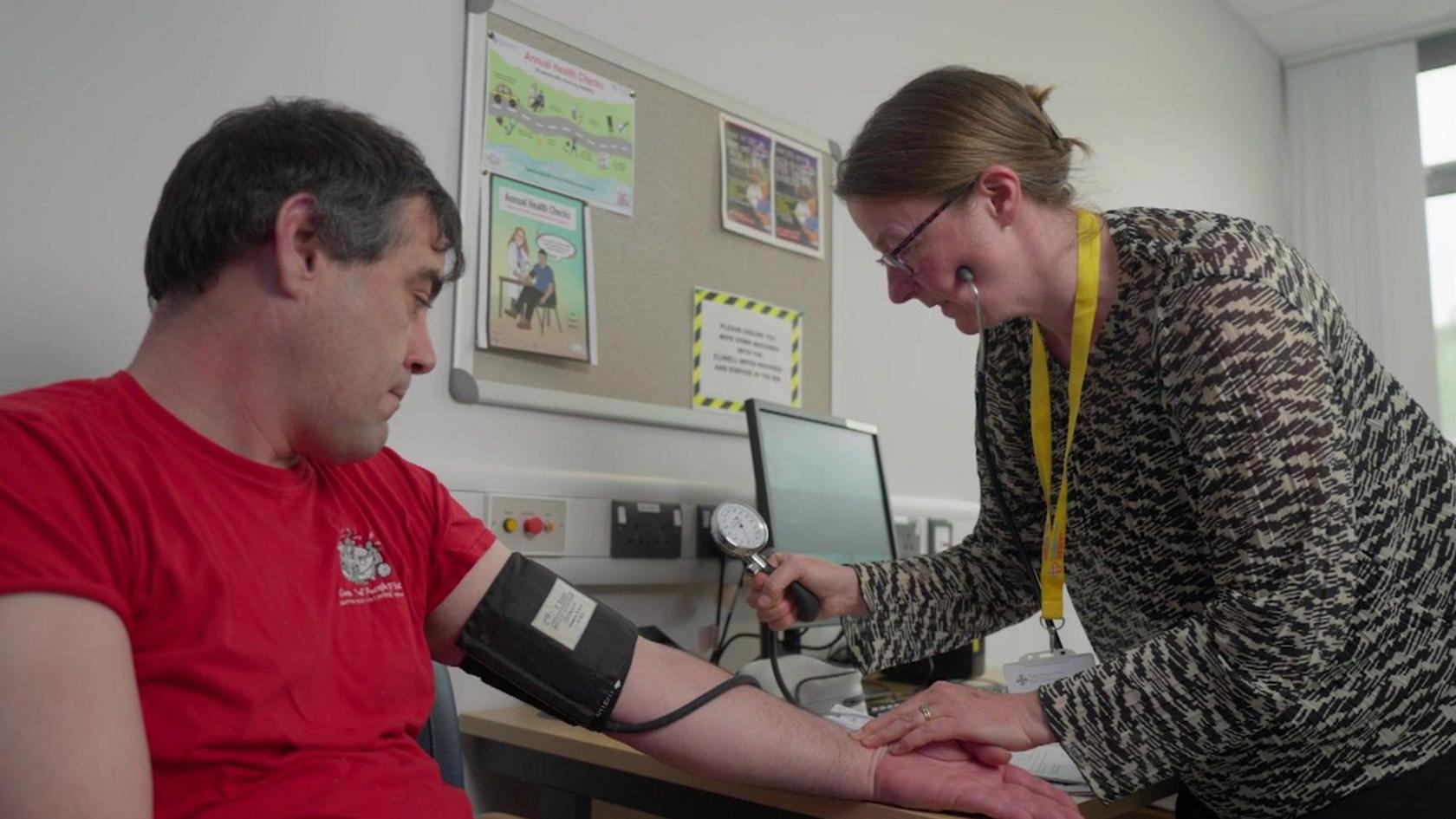 Tom is having his blood pressure taken by Dr Emma Hall in her clinic.