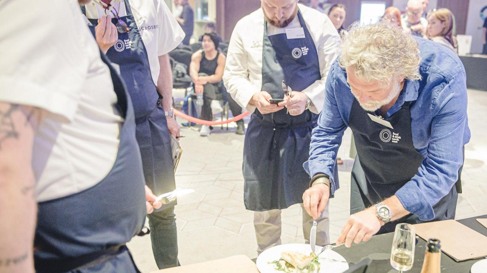 Si King tasting some food surrounded by other chefs