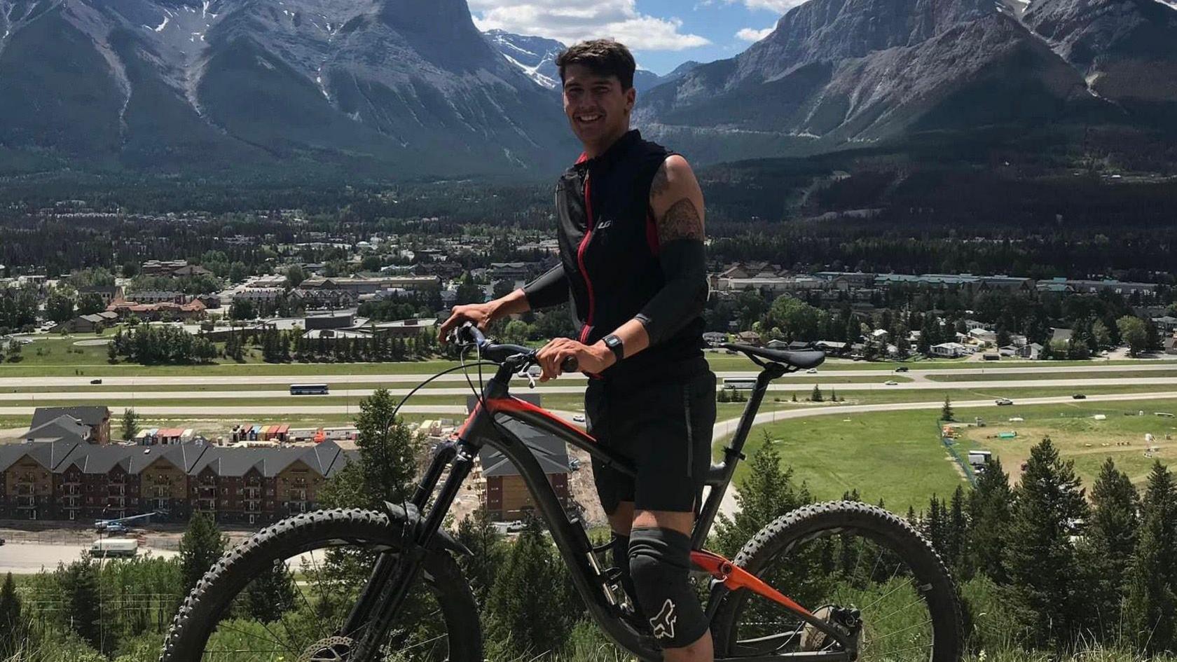 Cpl James Lloyd standing with a bike