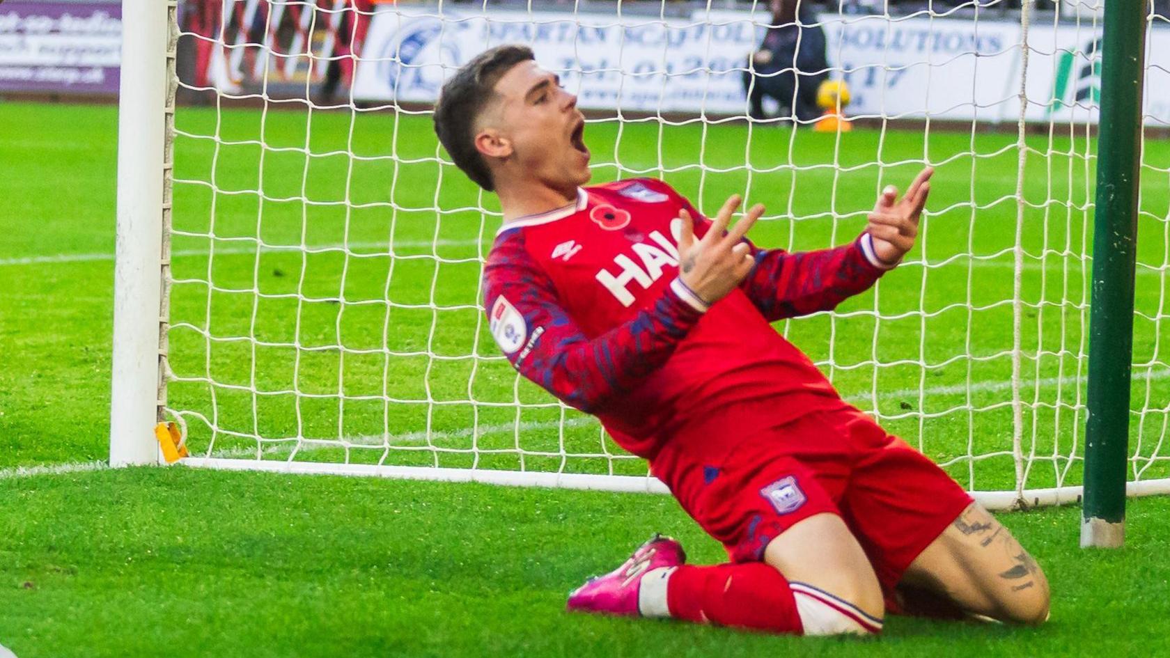 Leif Davis slides on his knees in celebration after scoring a goal for Ipswich