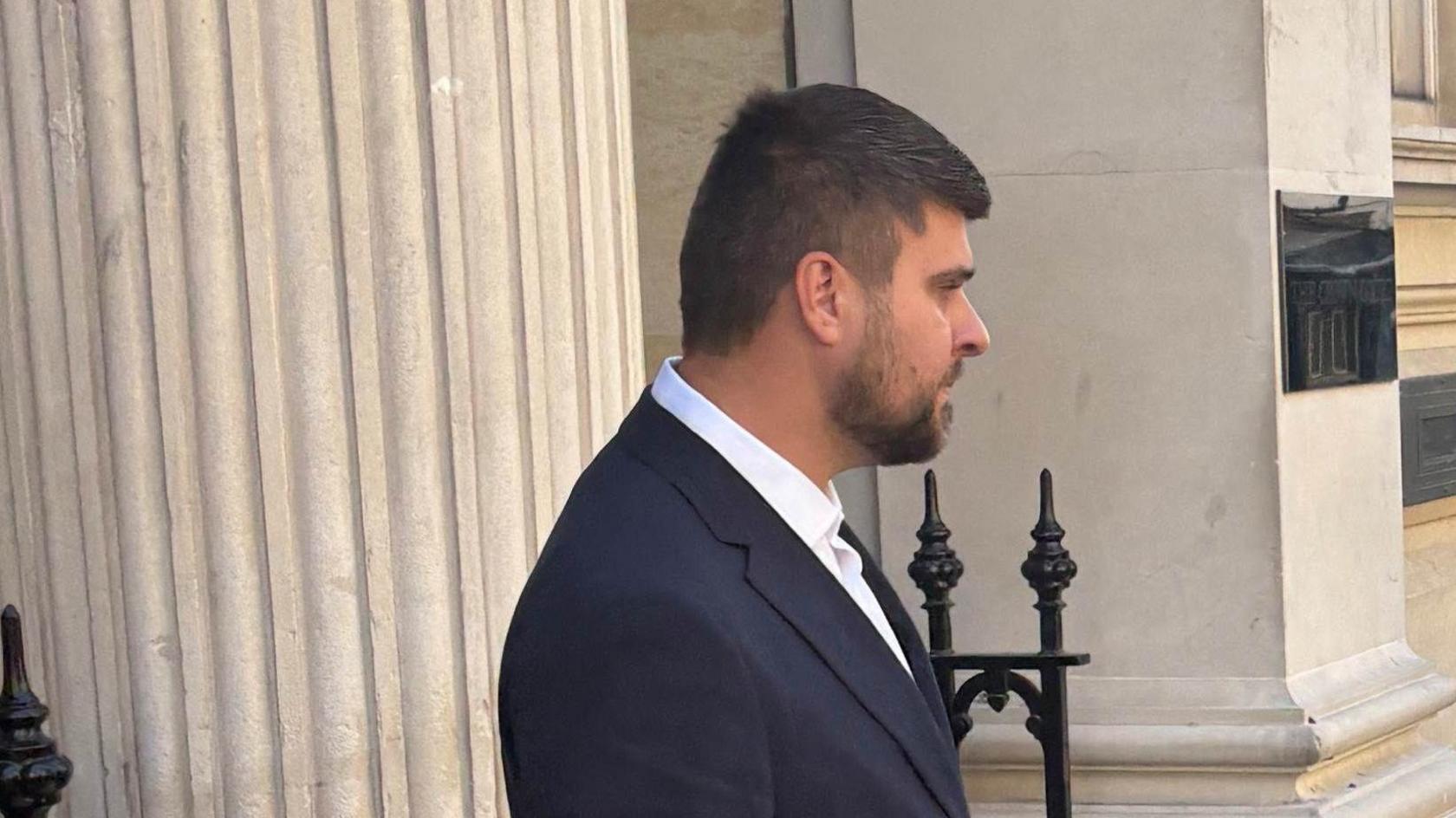 Joseph Gibson wearing a dark suit and white shirt leaves court.
