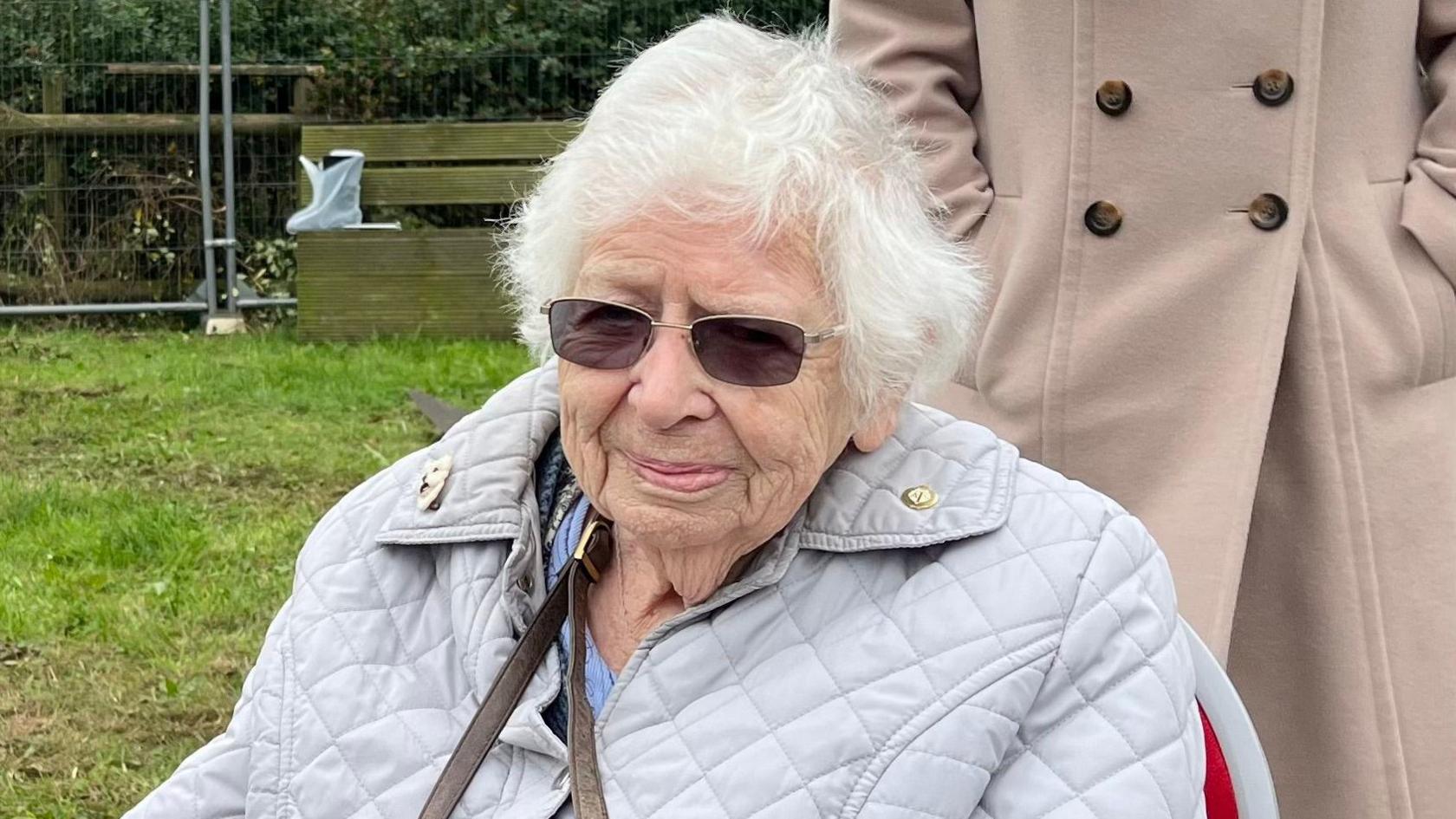 Margaret Bray wearing sunglasses and a jacket. She has short, white hair.