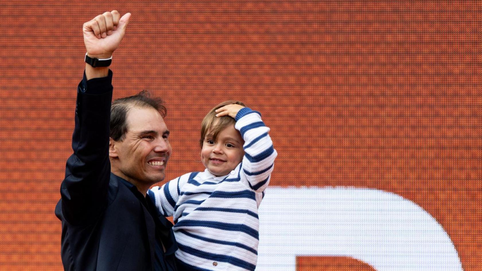 Rafael Nadal carries his son Rafael junior at the end of his French Open farewell ceremony