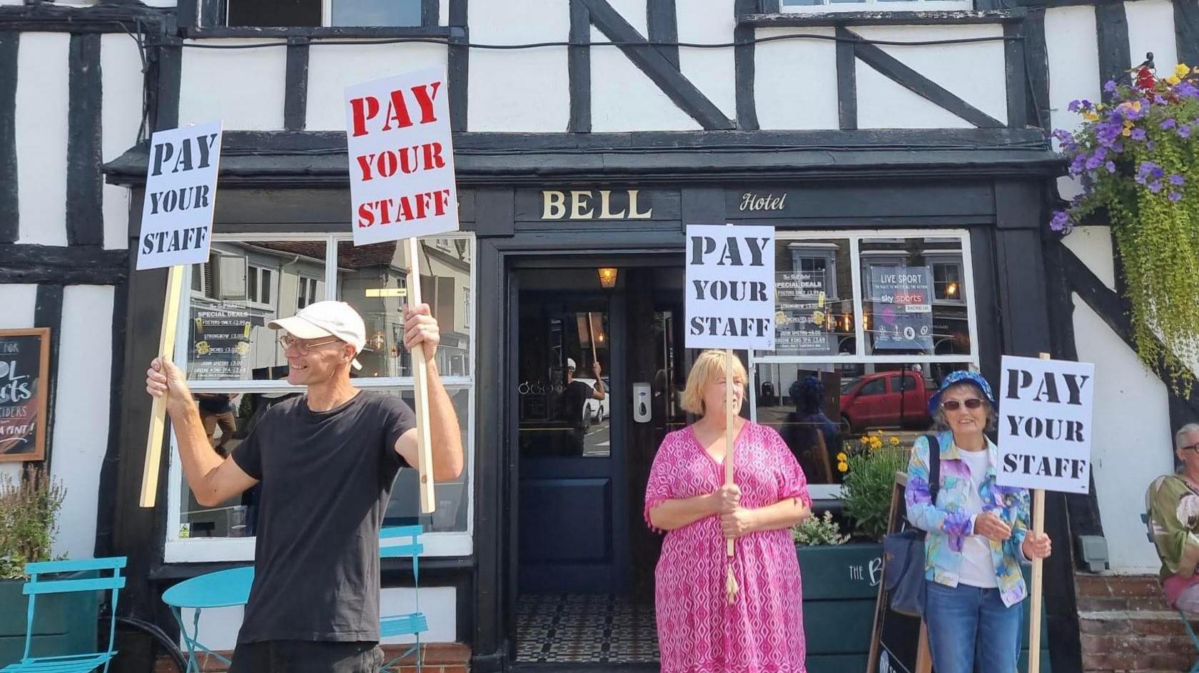 Men and woman holding placards protesting outside a pub