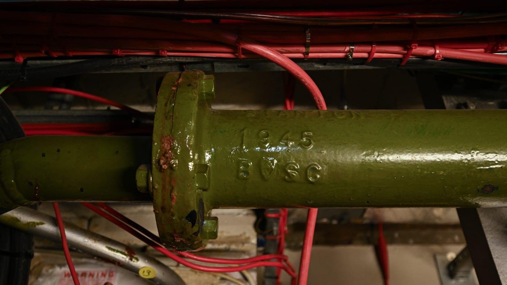 Një tub i gjelbër me vitin 1945 të stampuar anash. Pas tubit të gjelbër ka tela të kuq.