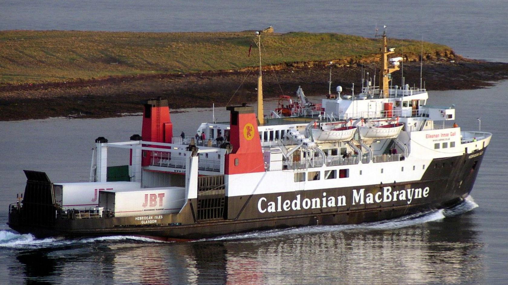 A black and white ship with red funnels sailing away from the camera with a headland in the background