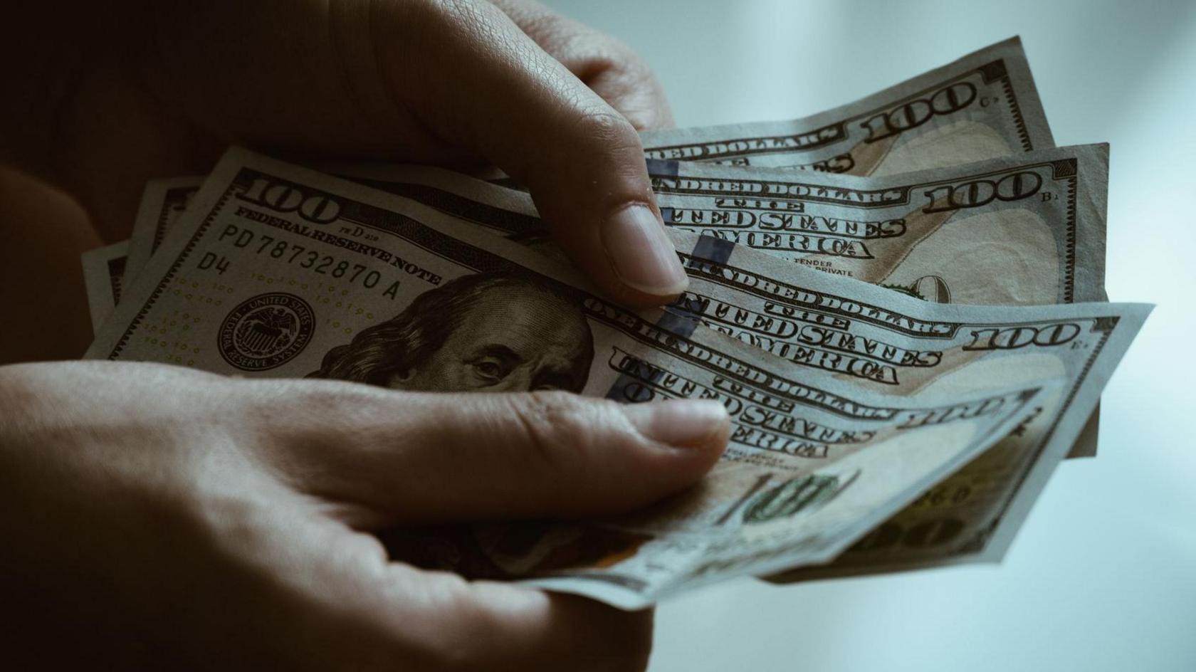 Close up of someone hands holding and counting American dollar banknotes in hands