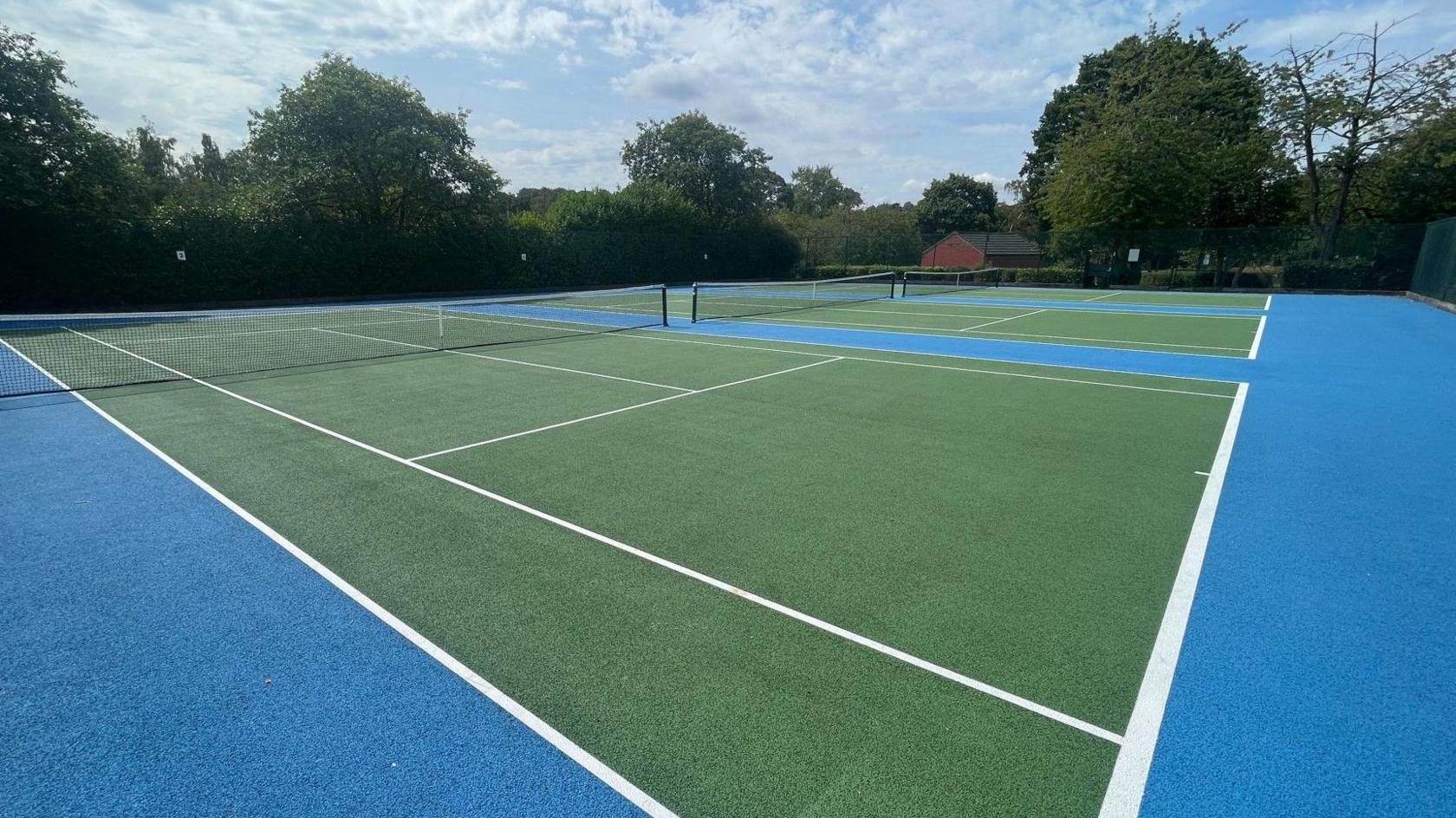 A newly refurbished outdoor tennis court in a public park in Leeds